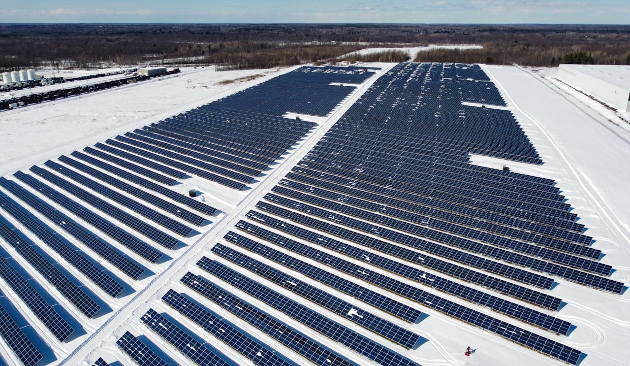 gallery-03 A drone-captured image of a large solar farm in Kingston, Canada, surrounded by snow.
