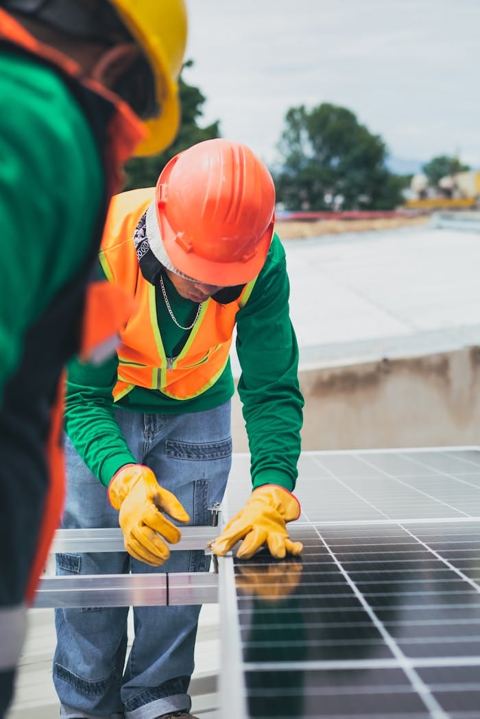 gallery-01 Worker in safety gear installing solar panels on a rooftop.